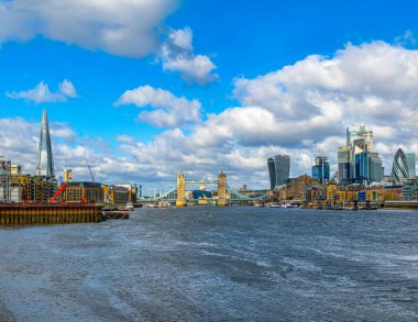 Londra 'nın Thames Nehri' nin panoramik manzarası gökdelenler ve sabah güneşiyle aydınlatılan Tower Köprüsü rıhtımlarına demirlemiş tekne ve feribotlar..