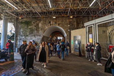 Demiryolu köprüsünün altından modern Borough Pazarı 'na giriş. Turistler sokaklarda geziniyor ve yemek yiyor..