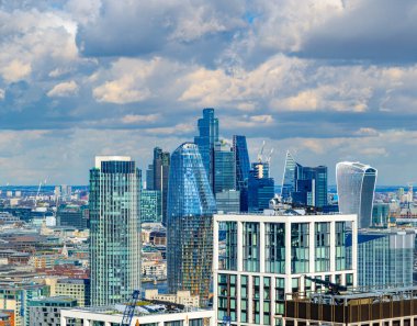 Londra 'nın ünlü binalarının panoramik hava manzarası ve finans bölgesinin gökdelenleri, şehrin ufuk çizgisinde vinçler, gökyüzünün altında ticari ofis binaları ve bulutlar tarafından aydınlatılmış bulutlar.