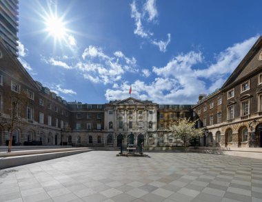 Terrazzo katlı bir manastır ya da avlu, Londra 'daki Guy' s Hospital 'ın bulutları altında mavi bir gökyüzünün altında şafak güneşiyle güzelce aydınlatılıyor. Birleşik Krallık.