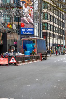 Londra 'nın merkezinde inşaat halindeki bir bina iskelesi ve koruyucu ekipmanlı işçiler bir kamyondan inşaat malzemelerini boşaltıyor..