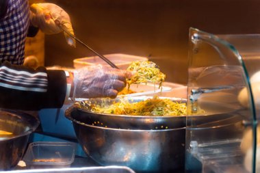 Önlük ve plastik eldiven takan Çinli şef, Çin Mahallesi 'ndeki Çin ve Asya restoranının mutfağında hamur köftesi yapmak için kasede malzemelerle yemek pişiriyor..