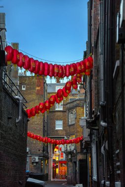 Dark alley of Chinatown with restaurant containers and only light source of red Chinese lanterns and the soft light of sunset under a clear blue sky. clipart