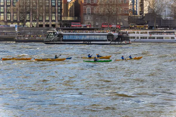 stock image Friends and families practicing water sports in kayaks and canoes on the River Thames and tourist pleasure boats alongside and tourist buses in the background.