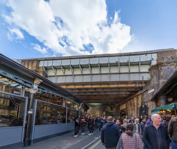 Demiryolu köprüsünün altından modern Borough Market 'e giriş, eski Lee Kardeşler Patates Tacirleri tabelası ile 1875' te pazara giriş yapıldı..