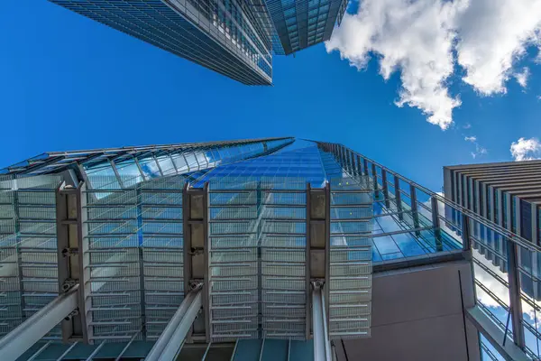 Düşük açı az modern mavi cam gökdelenin görüntüsü mavi gökyüzü ve pencerelerine yansıyan bulutlar. Londra mı? Birleşik Krallık.