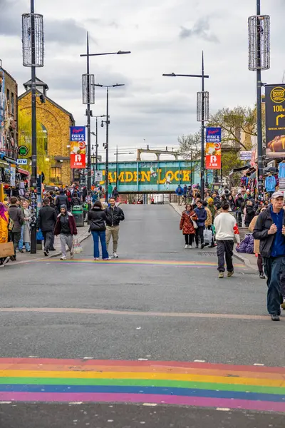 Camden Town Mahallesi 'nde Camden High Caddesi' nde birçok insan dükkanlara bakıyor ve lgbtiq 'in gökkuşağı renginde zebra geçitleri var.+