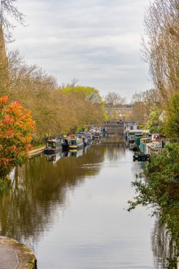Londra, Little Venice 'deki Maida Vale yerleşim bölgesindeki Regent Kanalı' na demirlemiş ahşap yüzen evler ve tekneler bulutlu bir gökyüzünün altında..