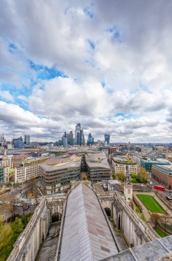 Londra 'nın St. Paul Katedrali' nin dikey hava manzarası. Şehrin modern gökdelenleri bulutlu bir gökyüzünün altında. Arka planda vinçler, gökdelenler ve modern binalar var..