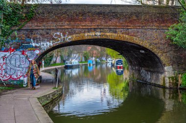 Londra 'nın küçük Venedik' inde bulunan Maida Vale yerleşim bölgesindeki Regent Kanalı üzerindeki tuğla bir köprüde alışveriş torbalarıyla gezinen bir kadın..
