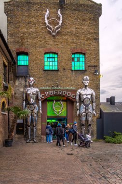 Camden Market 'in girişinde iki dev metal robotla birlikte efsanevi siber ve dans giyim mağazası Cyberdog' un yüzü. Londra.