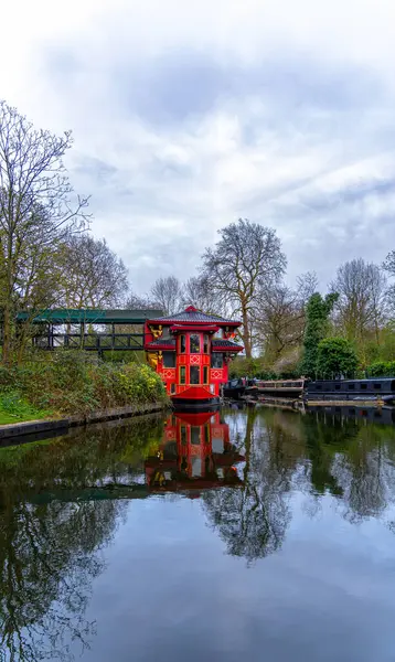Londra 'nın Maida Vale semtindeki Regents Park yerleşim bölgesinde yüzen kırmızı ahşap Çin restoranı. Regent Kanalı' nın kenarına yanaşmış ve teknenin suda simetrik yansımaları var..
