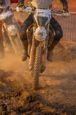 Bir off-road motosiklet ön manzara çamurlu arazide sürüş tekerlekler, botlar ve bisiklet ile çamurla kaplı bir kovalamaca bir dayanıklılık yarışı kaçma.