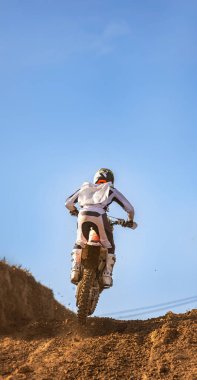 Motokros yarışçısının, motorsikletini bir motokros dayanıklılık yarışında bir tepenin üzerinden atlayıp çamurda yuvarlanmadan önce ön tekerleğini kaldırdığını gördüm..