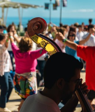 Barcelona 'da Katalan halk müziği çalan çellocu, deniz kenarındaki bir etkinlikte insanların dans ettiği Katalan sardansı çalıyor..