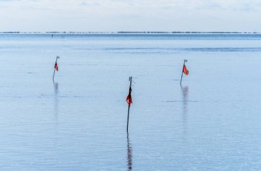 Akdeniz 'in sakin sularındaki kutuplarda dalgaların yüksekliğini ve arka planda ufuk olan balıkçılık alanlarını ölçmek için kırmızı bayraklar var..
