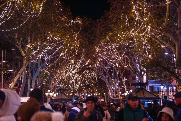 Noel ışıkları Barcelona 'daki La Rambla' daki ağaçları süslüyor. Soğuk bir kış gecesinde birçok insan Noel alışverişi için hediye almak için geziniyor..