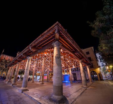 Tavandan sarkan metal prizmatik süslemelerle dolu tarihi Roma pazarı geceleri festival ışıklarıyla aydınlatılıyor..