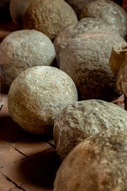 Medieval stone projectiles arranged on a tiled floor. clipart