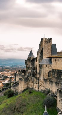 Fransa 'nın Carcassonne kentindeki ortaçağ kalesinin, ufukta bulutlu bir gökyüzünün altında, dağların ve Aude bölgesinin bulunduğu bir tepenin havadan görünüşü..