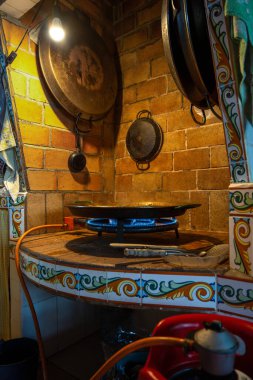 Valensiyalı paella, köy evindeki bir mutfakta yuvarlak bir gaz tavasında pişiriliyor..