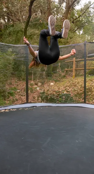 Ormandaki bir parkta trambolinde ters takla atan genç bir kadın..