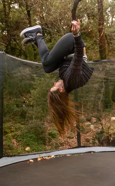 Genç bir kadın havada asılı kalmış, kafası aşağıda bir dağdaki trambolinde ters takla atıyor..