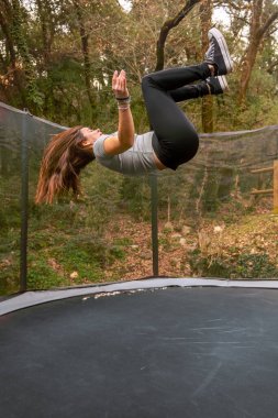 Genç bir kadın trambolinde ters takla atıyor..