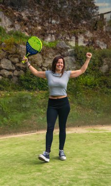 Genç, güçlü ve mutlu bir sporcu, dağlardaki açık havada oynanan tenis kortunda kollarıyla kazandığı raketi kutluyor..