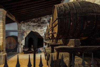 Eski bir şarap mahzeninin içinde büyük foudres ya da ahşap fıçılar, siyah işlenmiş demir bir çitin arkasında. Jerez de la Frontera, İspanya.