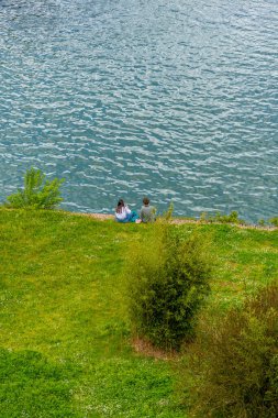Genç çift Fransa 'nın Albi kentindeki Tarn Nehri' nin yanındaki çimlerin üzerinde piknik yapıyor..