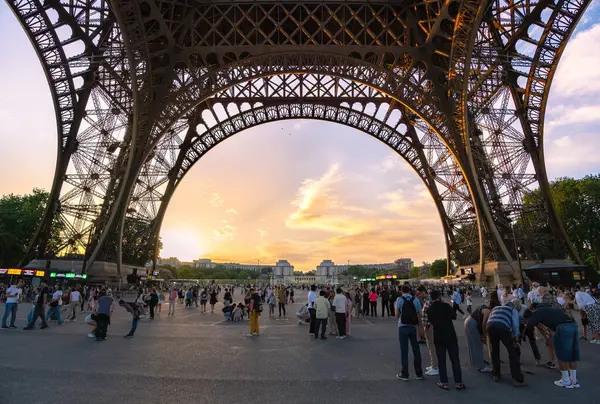 Turistler bir araya gelerek Paris, Fransa 'da gün batımında Eyfel Kulesi' nin altında fotoğraf çektiler..