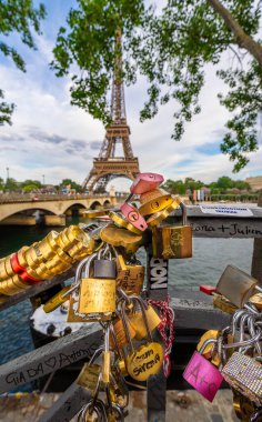 Paris 'teki Seine Nehri' nin yanındaki korkuluklara yazıtlı aşk kilitleri konur. Arka planda Eyfel Kulesi ve Pont des Arts bulunur..