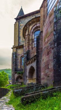 Sainte-Foy Manastırı Kilisesi 'nin dışı. Fransa' nın Conques kasabasındaki yeşil çimlerin arasında yosunla kaplanmış eski taş yalaklar..