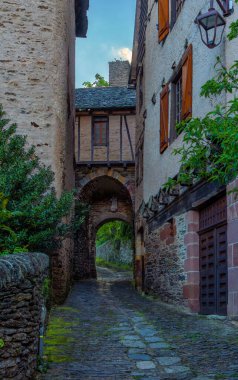 Fransa 'nın orta çağ köyü Conques' te yarı ahşap bir evin üzerinde orta çağ kaldırımlı bir sokak..