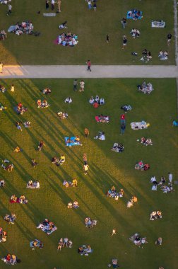 Gün batımında Champ de Mars 'ın yeşil çimlerine yansıyan uzun gölgeleri pikniklerin ve romantik yemeklerin keyfini çıkarıyor..