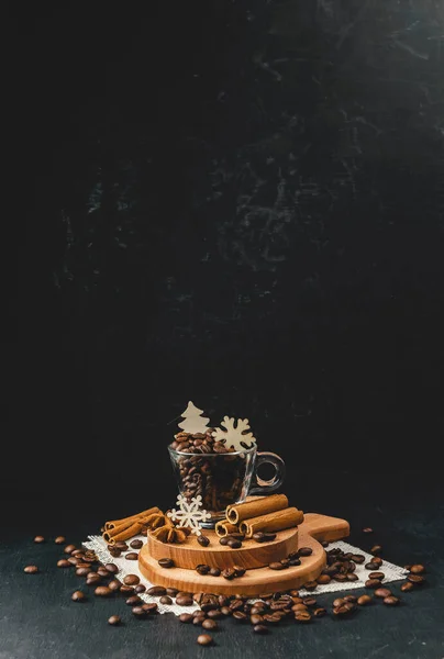 Aromatic coffee beans in a cup .Spiced coffee. Winter hot drink. Christmas. A hot drink will warm you on cold winter evenings. Winter decor and coffee grains on a dark background. New Year.