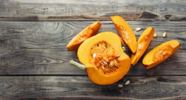 Şükran Günü. Kabaklar ahşap arka planda. Taze turuncu, büyük bir balkabağı ve tahta tahtada bir dilim balkabağı, yaklaşın. Organik sebze ürünleri, yemek malzemeleri, sağlıklı gıda vejetaryeni..