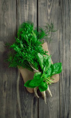 Ahşap arka planda dereotlu ve fesleğenli maydanoz. Taze organik maydanoz yaprakları. Doğal ve sağlıklı beslenme kavramı. Bahçeden. Yemek pişirmek. Vejetaryen yemeği. Faydalı bir ürün. Vitamin Salatası