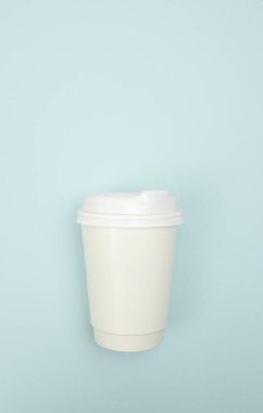 Sade mavi bir yüzey üzerinde tek kullanımlık kahve fincanının üst görünümü, promosyon veya iş sunumu içeriği için ideal  