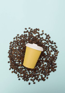 Sarı kağıt kahve fincanı ve kahve çekirdekleri mavi arka planda. Üst Manzara. Düz yatıyordu.