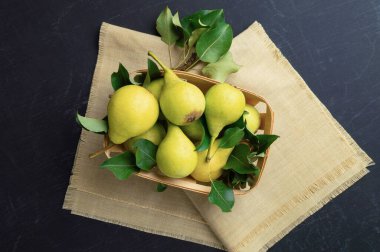 Armutlar. Tahta kutuda yaprakları olan taze organik armutlar veya eski koyu gri arka planda sepet. Sonbahar meyve hasadı. Üst Manzara. Yemek arkaplanı. Üst manzara, düz yatış. Kopyalama. Pankart.