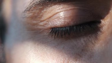 Erkek gözü gün batımında açılıp kapanıyor. Yakın planda. Ağır çekim..