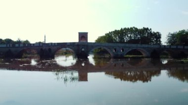 Edirne 'deki Osmanlı İmparatorluğu' ndan ünlü bir taş köprü. Kesik taştan yapılmış klasik kemerli tarihi bir köprü. Arka planda minarenin silueti ve minarenin yapısı görülebilir..
