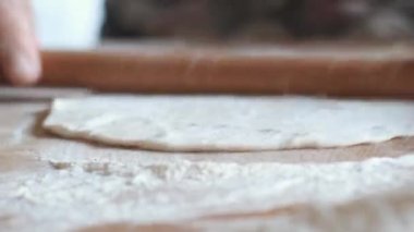Eller merdaneyle hamuru yuvarlıyor. Köyde ev yapımı lavaş tipi ekmek hamuru yapılır. Kamera bir döngü hareketiyle hareket eder..