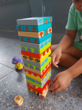 Evin terasında oynayan bir çocuğun yakın çekimi var. Eli oyuncağını tutuyor..