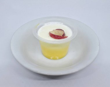 Üzüm soslu mango aromalı meyveli puding, küçük plastik bir kabın içinde. Beyaz izole.