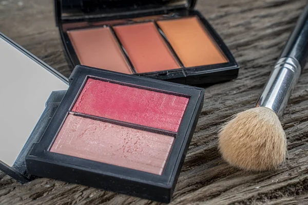 A palette of double blush for the face behind triple blush palette and brush .Make-up products