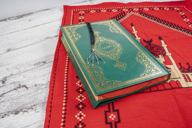 El yapımı kırmızı halıya Kur 'an ve tespih. Ramazan kutsanmıştır..