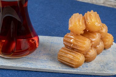 Geleneksel Türk tatlı tulumbası, ahşap bir tabakta çay ile servis edilen tulumba tatlisi.